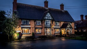 A traditional brick building with a sign for 'The Bear's Head' pub, a visible entrance, and a bench outside. - The Bears Paw Inn (Sandbach)