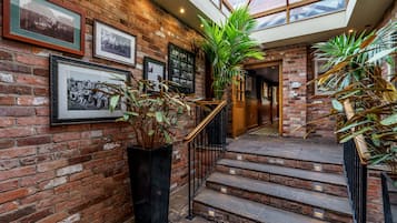 A brick-walled staircase with a glass ceiling, leading to a wooden door.
