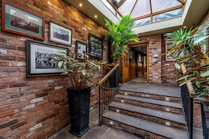 A brick-walled staircase with a glass ceiling, leading to a wooden door. - The Bears Paw Inn (Sandbach)