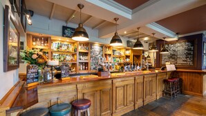 A bar with wooden counters, hanging pendant lights, and a chalkboard menu. - The Bears Paw Inn (Sandbach)