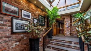 A brick-walled staircase with a glass ceiling, leading to a wooden door. - The Bears Paw Inn (Sandbach)
