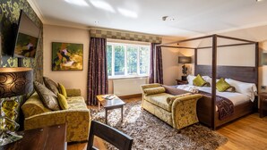 A four-poster bed, a sofa, a chair, a small table, and a TV mounted on the wall. - The Bears Paw Inn (Sandbach)