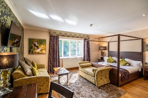 A four-poster bed, a sofa, a chair, a small table, and a TV mounted on the wall. - The Bears Paw Inn (Sandbach)