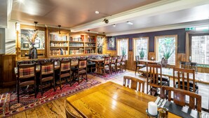 Een bibliotheek met boekenplanken, een houten tafel en stoelen.