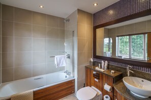 A modern bathroom with a bathtub, shower, toilet, vanity with a sink, and a large mirror. - The Bears Paw Inn (Sandbach)