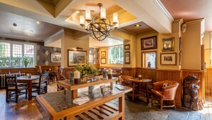 A spacious dining area with wooden tables and chairs, a central island with a marble top, and a chandelier. - The Bears Paw Inn (Sandbach)