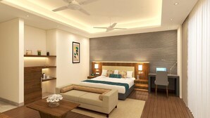A modern hotel room with a large bed, a desk, a sofa, and a ceiling fan. - The Fern - An Ecotel Hotel, Alwar (Alwar)