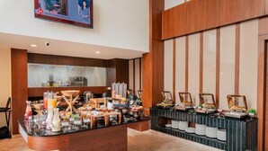 A buffet area with a variety of food items and beverages, a television mounted on the wall, and a wooden panel design on the walls. - The Fern - An Ecotel Hotel, Alwar (Alwar)