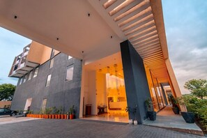 A modern building with a large entrance, a covered walkway, and potted plants. - The Fern - An Ecotel Hotel, Alwar (Alwar)