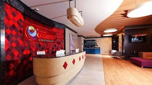 A reception area with a modern design, featuring a curved reception desk, a logo on the wall, and a television screen.