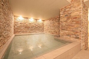 Een wellnessruimte met een stenen muur en een glazen hottub.