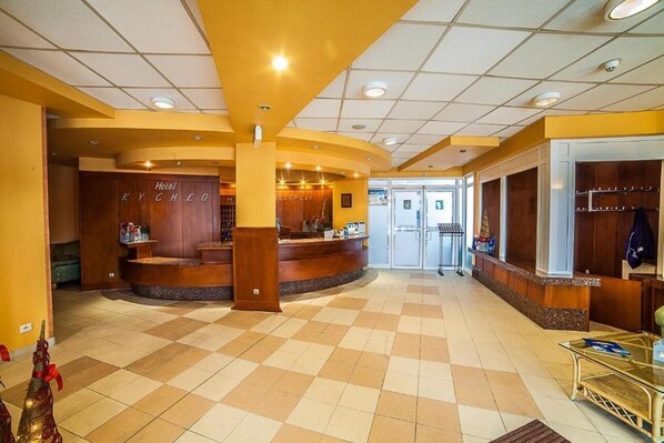A hotel lobby with a reception desk, a coat rack, and a check-in counter. - Hotel Rychlo (Bogatynia)