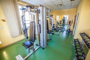Un gimnasio con diverso equipo de ejercicio, incluyendo máquinas de pesas y mancuernas.