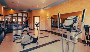 Un gimnasio con cintas de correr, elípticas y pesas libres.