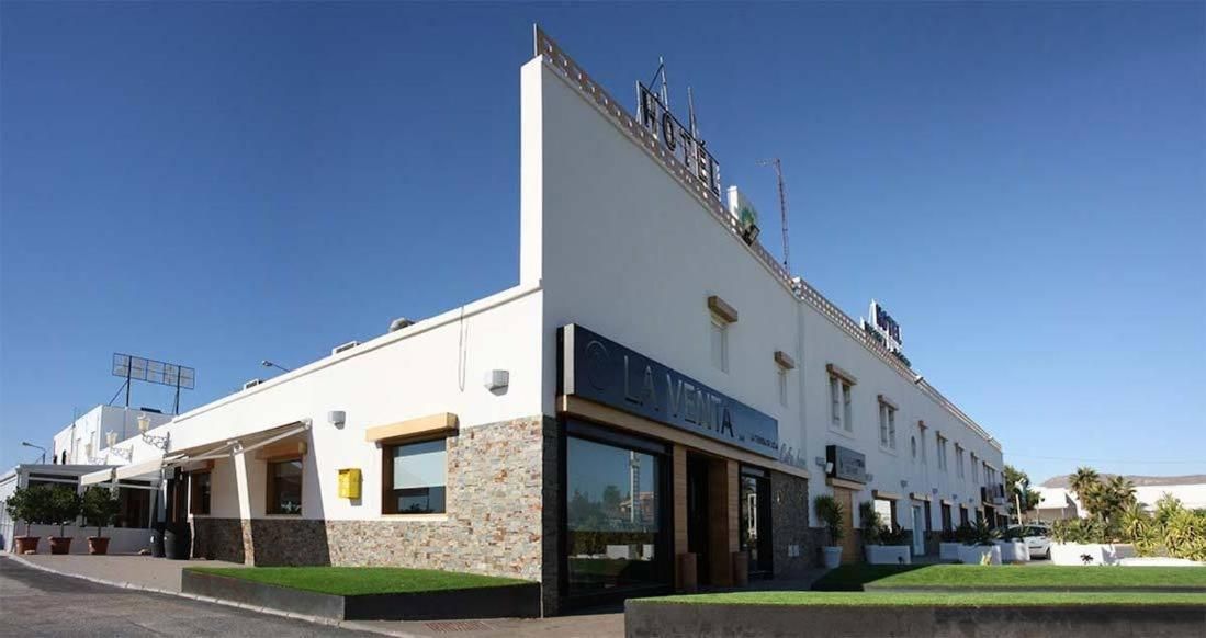 Un hotel con fachada plana, ventanas amplias y un letrero que indica que es un hotel.