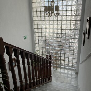 A staircase with a wooden railing leading to a room with a large window featuring a grid pattern. - Hotel Venta del Pobre (Nijar)