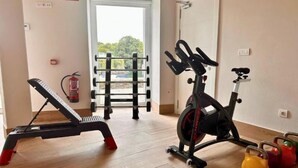 Un gimnasio con equipo de ejercicio que incluye una cinta de correr, bicicleta estática y pesas de kettlebell.