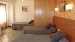 Une chambre d’hôtel avec deux lits simples, une tête de lit en bois, une petite table et une chaise.