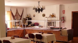 Un espace repas avec des tables et des chaises, un buffet et un lustre.