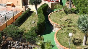 Un espace piscine agrémenté de chaises longues, d’un chemin en pierre et d’une végétation luxuriante.