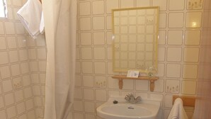 Une salle de bain avec une baignoire, un lavabo et des toilettes, des murs carrelés et un miroir.