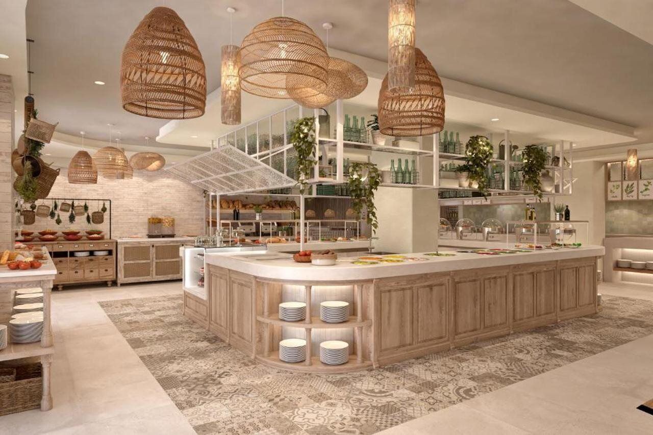 A modern kitchen with a central island, hanging wicker chandeliers, and a staircase leading to an upper level.
