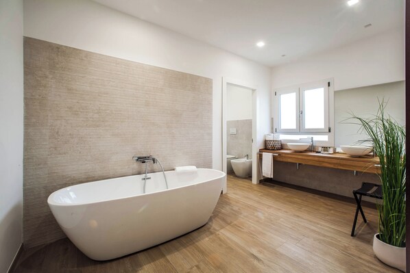 A modern bathroom with a freestanding bathtub, a wooden vanity with a sink, and a large mirror. - Noha Lifestyle - Adults Only (Pula)