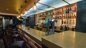 A bar area with wooden bar counters, hanging light fixtures, and shelves stocked with various liquor bottles. - Hotel Novo Candido (Ourense)