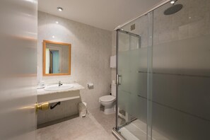 Une salle de bain moderne avec une douche à parois de verre, un lavabo avec un miroir et des toilettes.