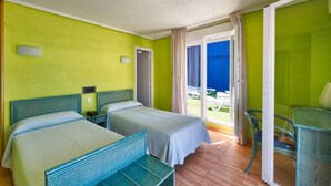 A hotel room with two beds, a desk, and a chair. There is a sliding glass door leading to a balcony. - Hotel Marina (Oropesa del Mar)