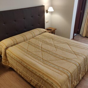 A bedroom with a large bed, a dark headboard, a bedside table with a lamp, and a wooden floor. - Hotel Chef Rivera (Padron)