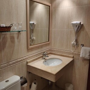 A bathroom with a sink, mirror, hairdryer, and toilet. - Hotel Chef Rivera (Padron)