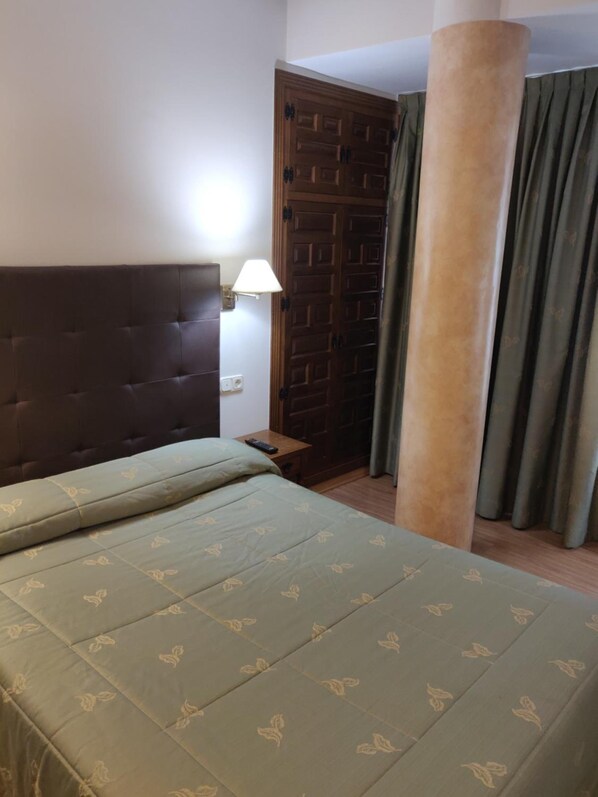 A bedroom with a large bed, a wooden wardrobe, a nightstand, and a lamp. - Hotel Chef Rivera (Padron)