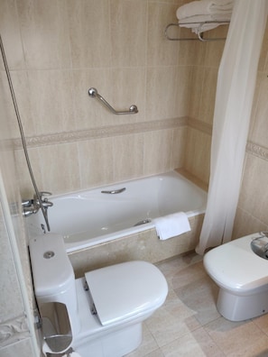 Une salle de bain avec une baignoire, des toilettes et une douche.