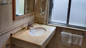 Un baño con lavamanos, espejo y toallero.