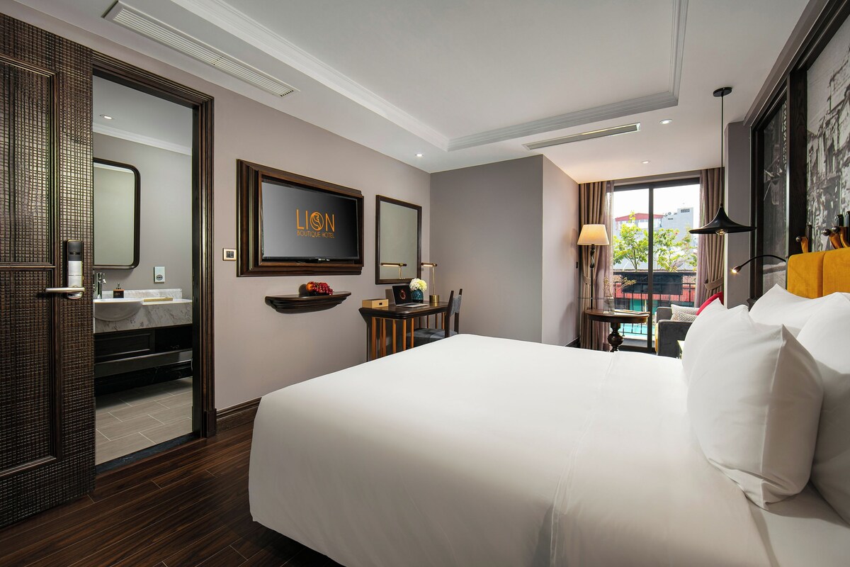 Ein Hotelzimmer mit einem großen Bett, einem Fernseher, einem Schreibtisch mit Stuhl, einem Fenster mit Blick und einem Badezimmer mit Spiegel und Waschbecken.