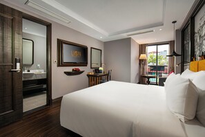Une chambre d’hôtel avec un grand lit, une télévision, un bureau avec une chaise, une fenêtre donnant sur un beau paysage et une salle de bain avec un miroir et un lavabo.