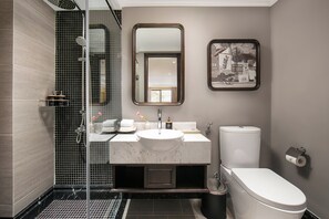 Een moderne badkamer met een douchecabine van glas, een witte wastafel en een toilet.