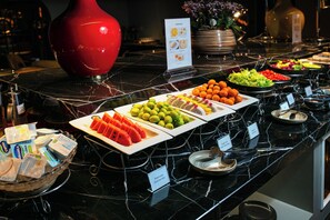 Un buffet proposant divers plats et un vase rouge posé sur le comptoir.