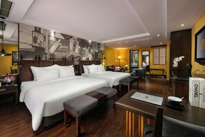 Een hotelkamer met twee bedden, een bureau, een laptop, een televisie en een groot wanddecor.