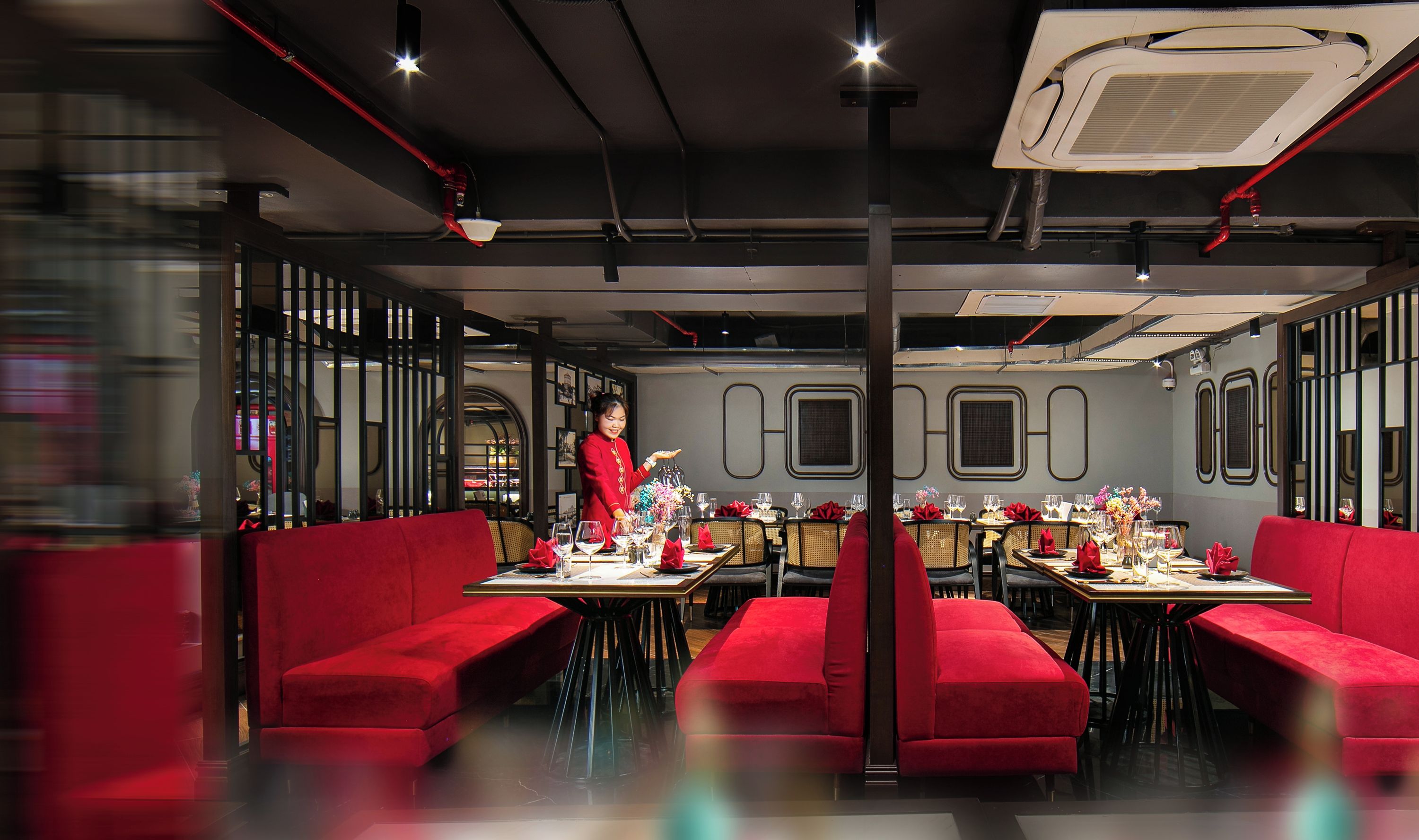 A modern restaurant interior with red seating, a waitstaff, and a contemporary design.