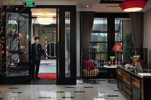 A hotel lobby with a reception desk, a red carpet, and a view of the street through large windows. - Ha Noi Lion Boutique Hotel (Hanoi)