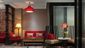 A modern hotel lobby with a red sofa, a round table, and a staircase with a red pendant light. - Ha Noi Lion Boutique Hotel (Hanoi)