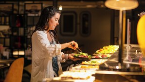 A person serving food at a buffet with various dishes visible. - Ha Noi Lion Boutique Hotel (Hanoi)