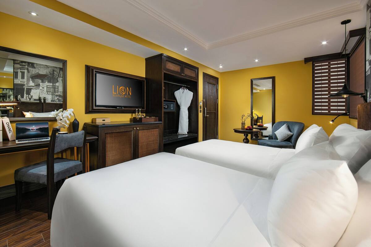 Habitación de hotel con dos camas, televisión, armario, escritorio con silla y espejo.
