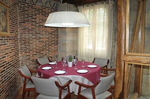 Un comedor con pared de ladrillo, una mesa redonda para cuatro comensales y una lámpara colgante grande.