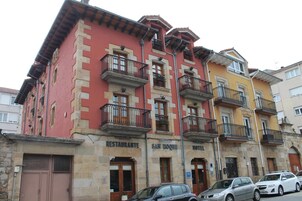 Un edificio de varios pisos con un restaurante en la planta baja y un hotel en el segundo piso, y balcones con barandillas.
