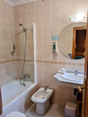 A bathroom with a bathtub, a bidet, a sink, and a toilet. - Hotel San Roque (Reinosa)