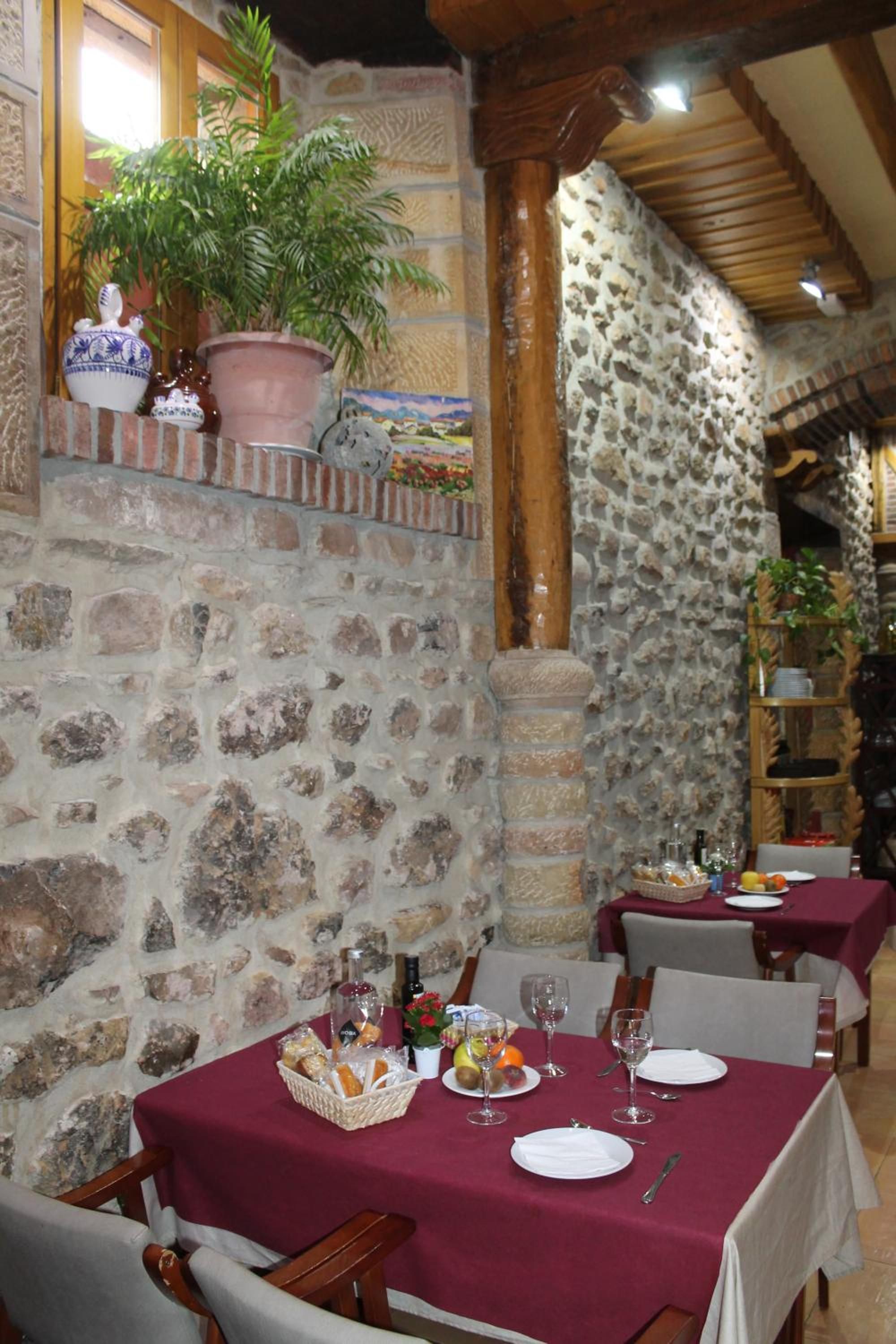 Un restaurante con paredes de piedra, vigas de madera y mesas dispuestas para comer.