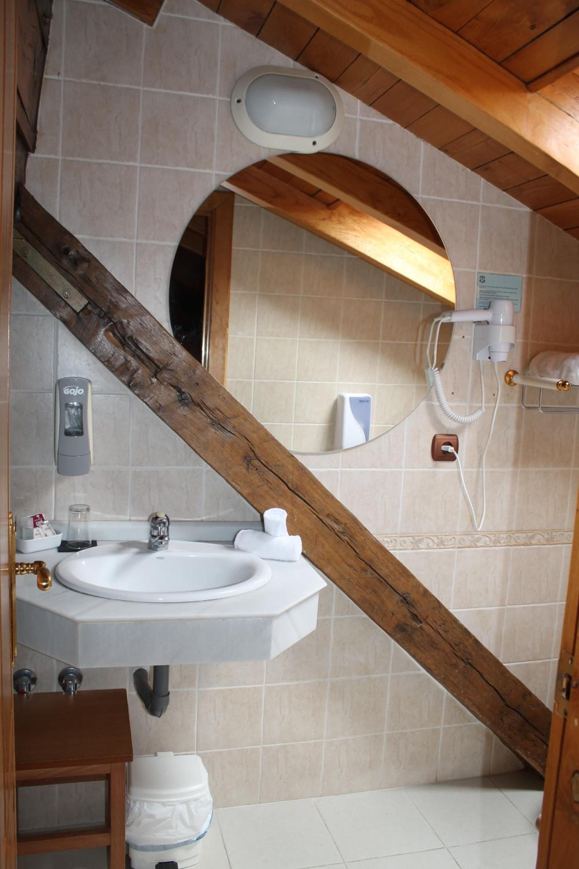 Un baño con lavamanos blanco, un espejo, una toalla y una zona de ducha.